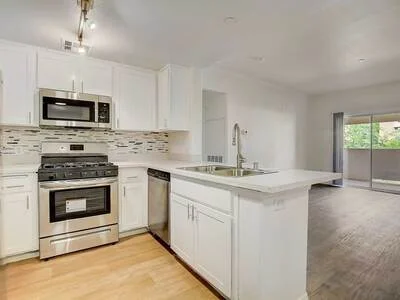 Apartment kitchen with white cabinets and view of the living room